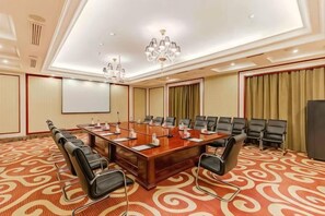 A conference room with a large oval table, multiple chairs, a projector screen, and a carpeted floor. - Hongxing International Hotel (Jing County)