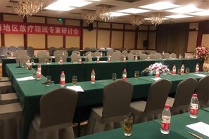 Un salón de conferencias con largas mesas, sillas y un cartel en la pared.