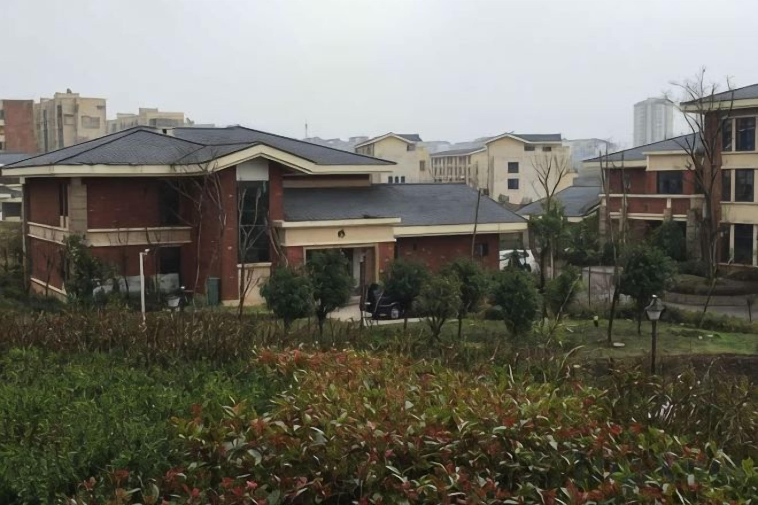Un barrio residencial con varias casas de dos pisos, algunas con balcones, rodeado de vegetación y algunos árboles.
