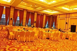 Un salón de banquetes con mesas redondas, sillas y piso alfombrado.