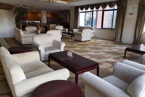 A hotel lobby with multiple seating areas, a large window with curtains, and a patterned carpet. - Hongxing International Hotel (Jing County)