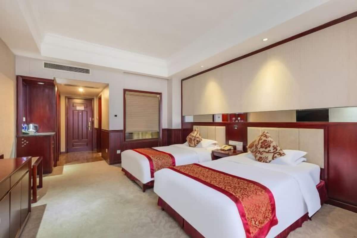 A hotel room with two beds, a desk, and a minibar.
