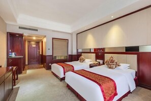 A hotel room with two beds, a desk, and a minibar.