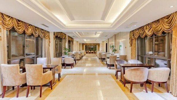 A hotel lobby with a long corridor, seating areas, and large windows. - Hongxing International Hotel (Jing County)