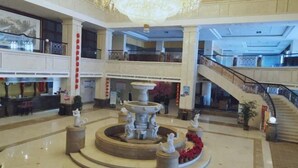 A spacious lobby with a central fountain, multiple floors, and a staircase. - Hongxing International Hotel (Jing County)