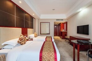 A hotel room with two beds, a TV, a desk, and a mirror.