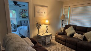 A cozy living room with a brown sofa, a white armchair, and a small table with a lamp and decorative items. - Salisbury Bungalow (Salisbury)
