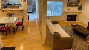 A living room with a sofa, a dining table with chairs, a kitchen area with a refrigerator, and a fireplace. - Sweet 3 Bedroom condo in Hacienda Heights (Hacienda Heights)