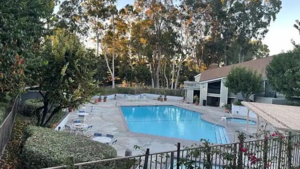 A swimming pool with a deck area, surrounded by trees and a building. - Sweet 3 Bedroom condo in Hacienda Heights (Hacienda Heights)