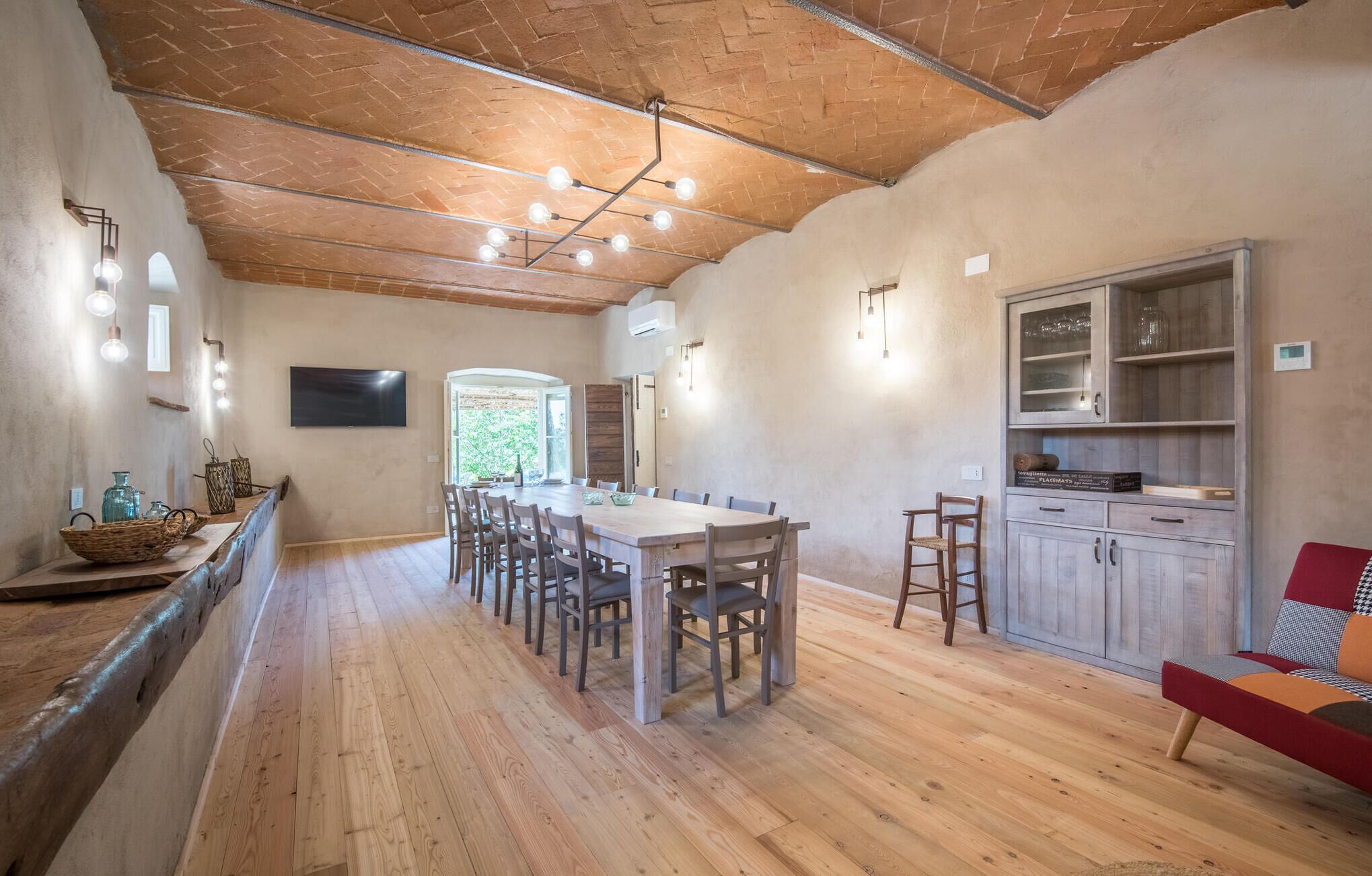 Ein geräumiger Essbereich mit einem langen Holztisch und Stühlen, eine Küche mit Holzschränken und ein großes Fenster, das natürliches Licht hereinlässt.