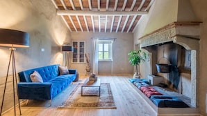 Un loft espacioso con vigas de madera a la vista, un sofá azul, una chimenea y un ventanal grande.