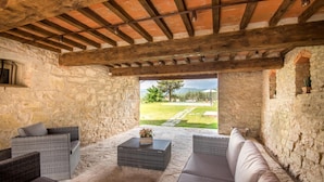 Una habitación rústica de piedra con techo de madera, amueblada con sofás de mimbre y una mesa de centro.