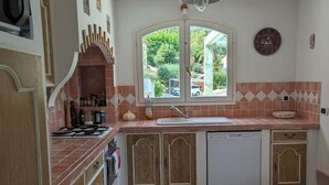 A kitchen with a window, a sink, cabinets, and a ceiling fan.