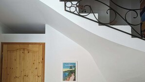 A bedroom with a wooden door, a bed with pillows, a wicker basket, and a poster on the wall.