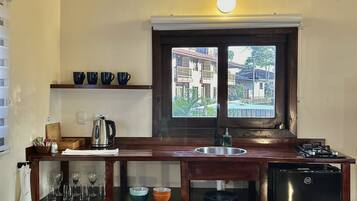 Una cocina con vigas de madera, un ventanal con vistas, un lavamanos y un refrigerador.