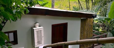 Ein weißes Gebäude mit roter Tür, kleinem Fenster und Lüftungseinheit.