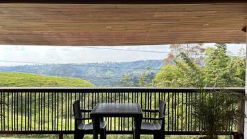 Ein Balkon mit Tisch und Stühlen mit Blick auf eine hügelige Landschaft.