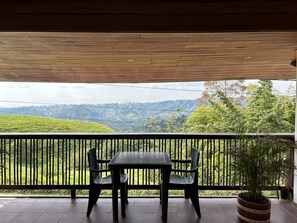 Een balkon met een tafel en stoelen met uitzicht op een glooiend landschap.