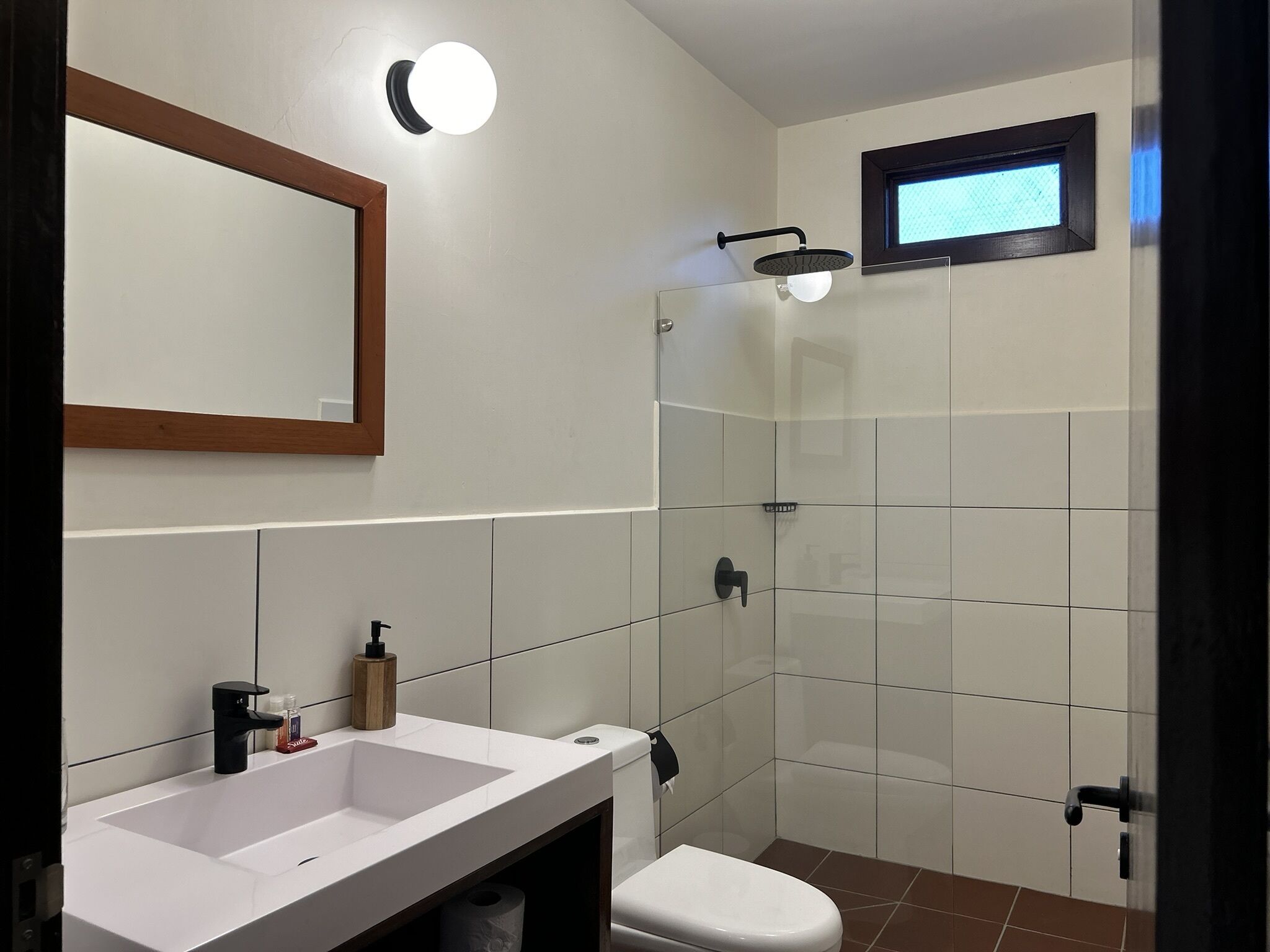 Een badkamer met een wit wastafelmeubel, toilet en een douchecabine met glazen wanden.