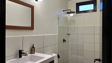 Een badkamer met een wit wastafelmeubel, toilet en een douchecabine met glazen wanden.