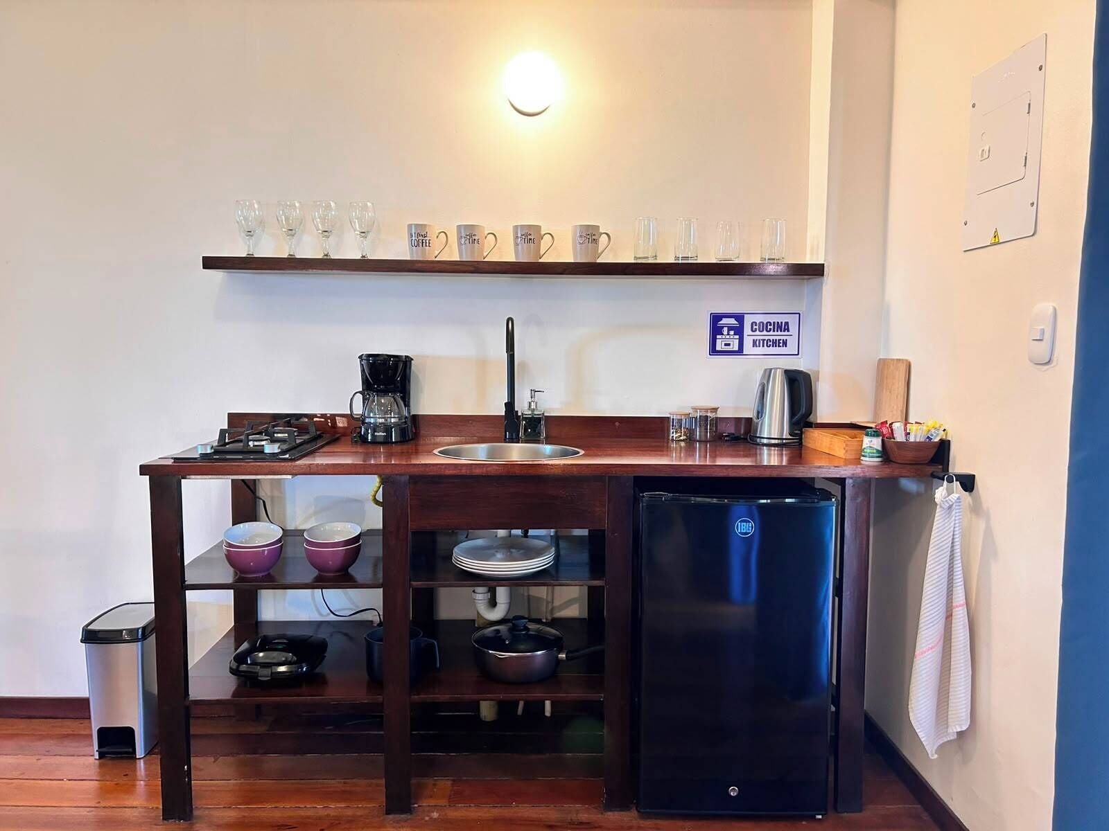A compact kitchenette with a coffee maker, sink, and a refrigerator.