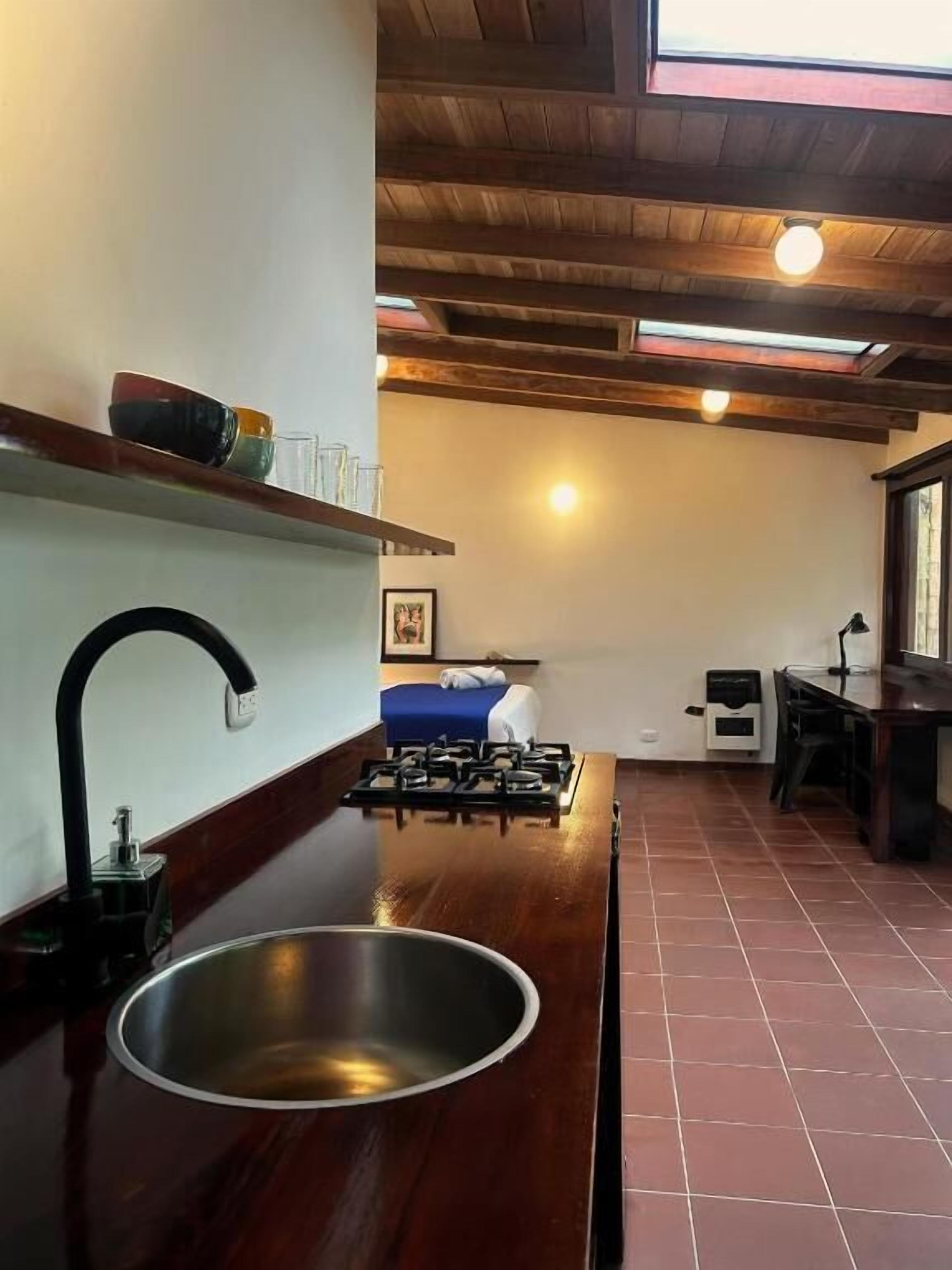 A kitchen with a stainless steel sink, a gas stove, and a wooden countertop.