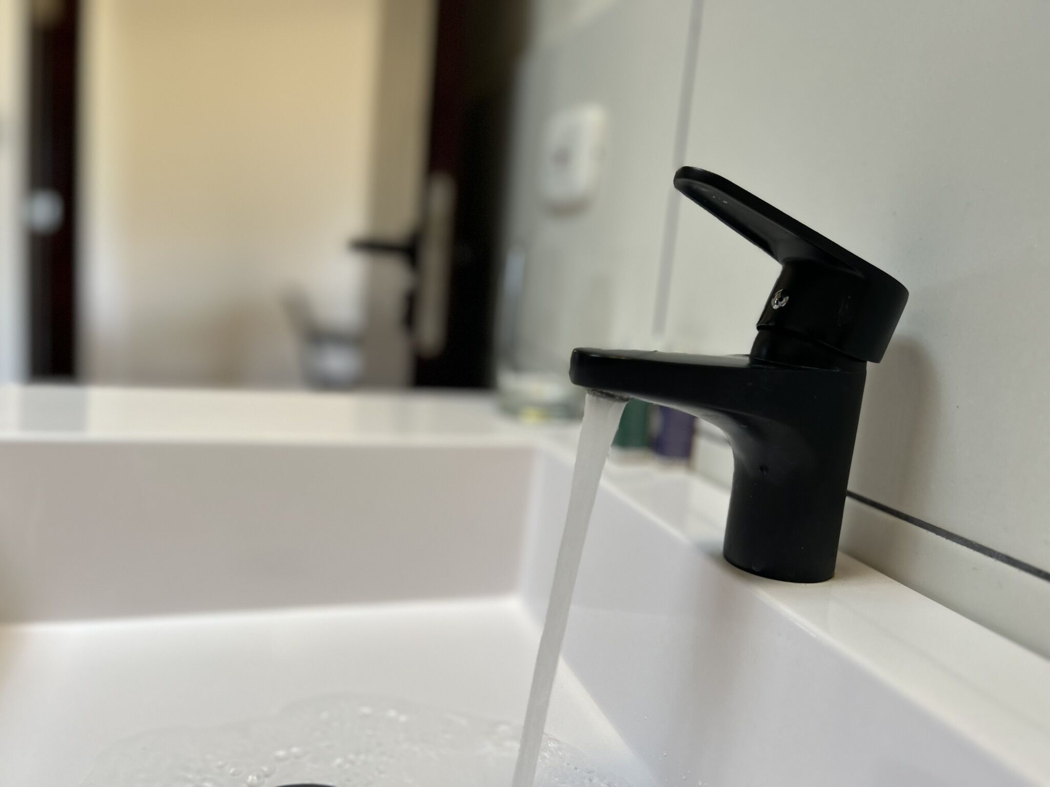 A bathroom sink with a black faucet and running water.