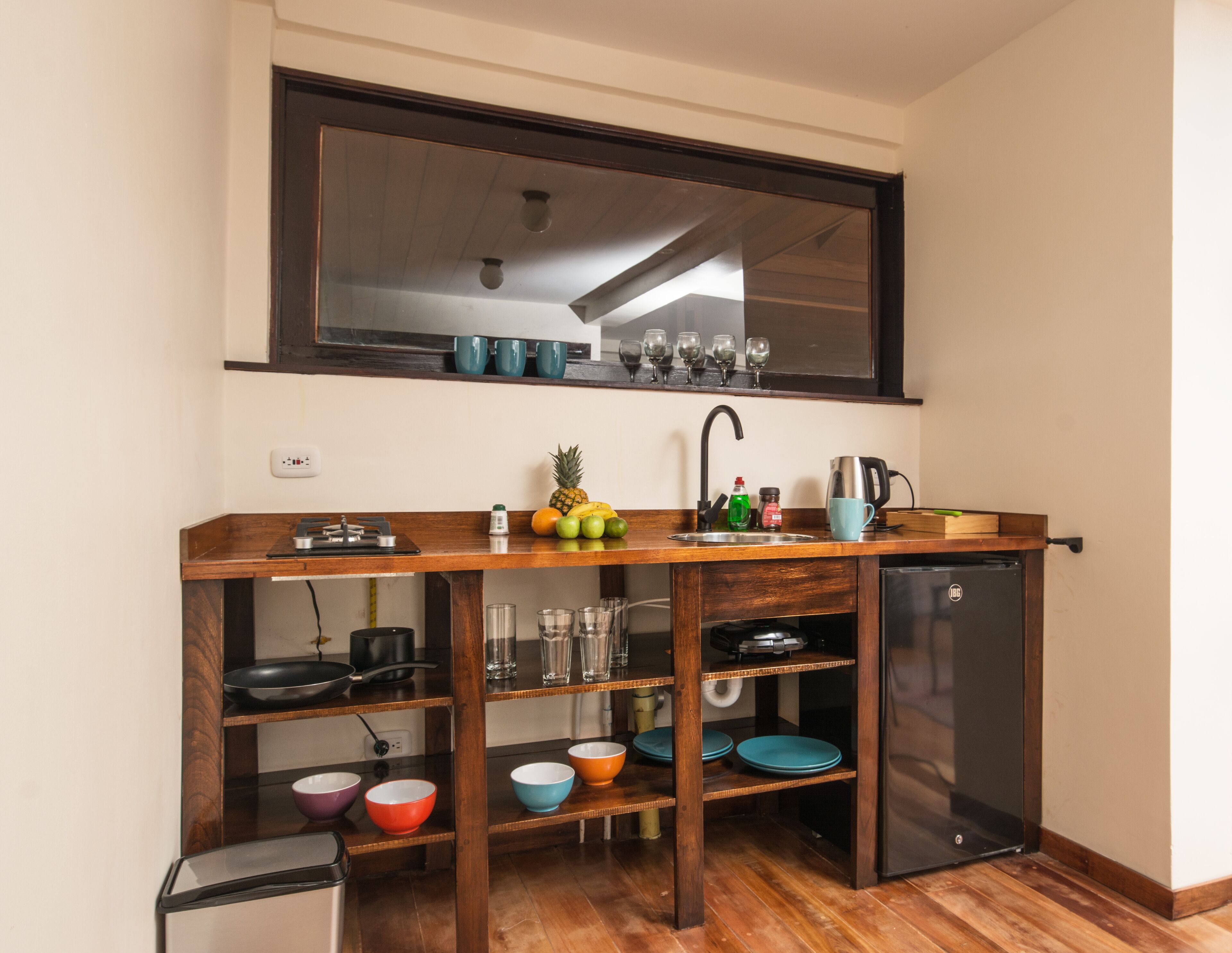 A compact kitchen with a wooden countertop, a built-in sink, and a small refrigerator.