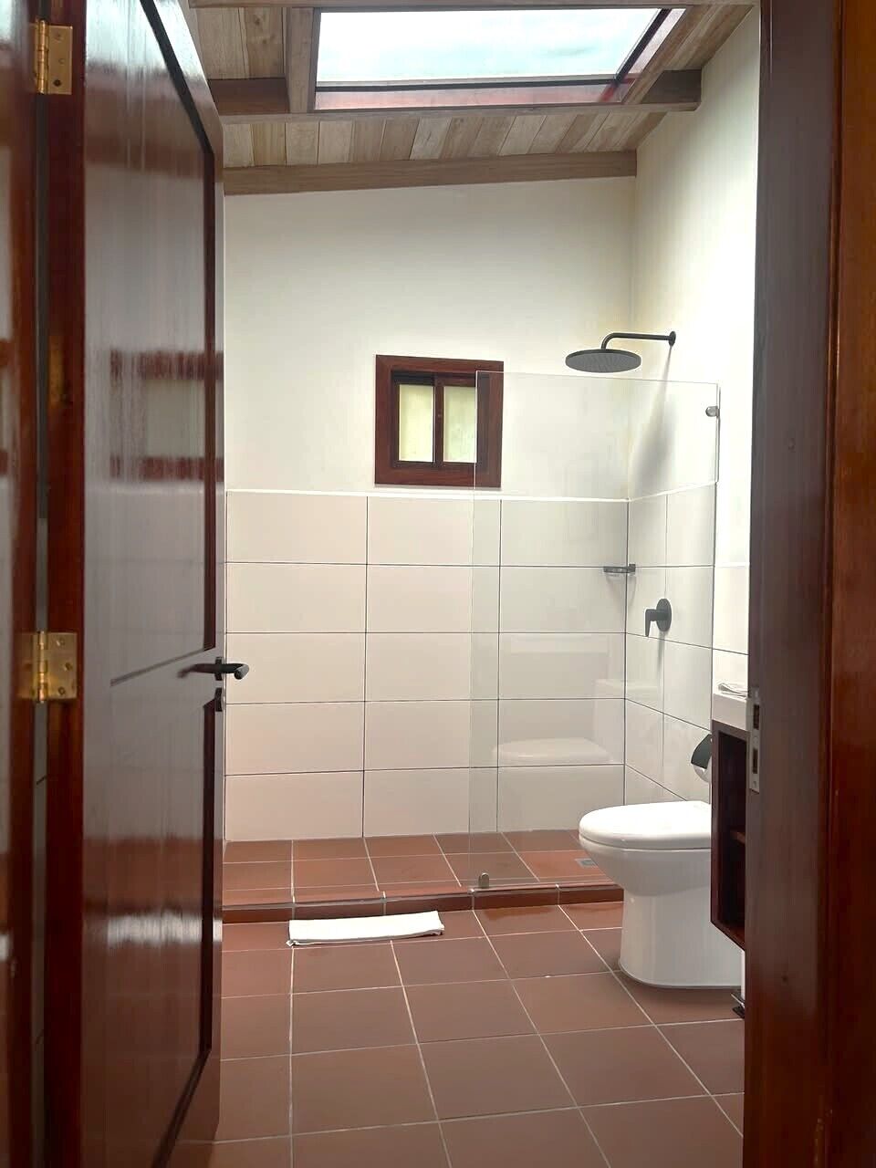 A bathroom with a shower, toilet, and a skylight.