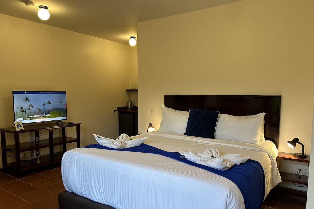 Ett hotellrum med en säng, en tv, ett skrivbord och ett nattduksbord.