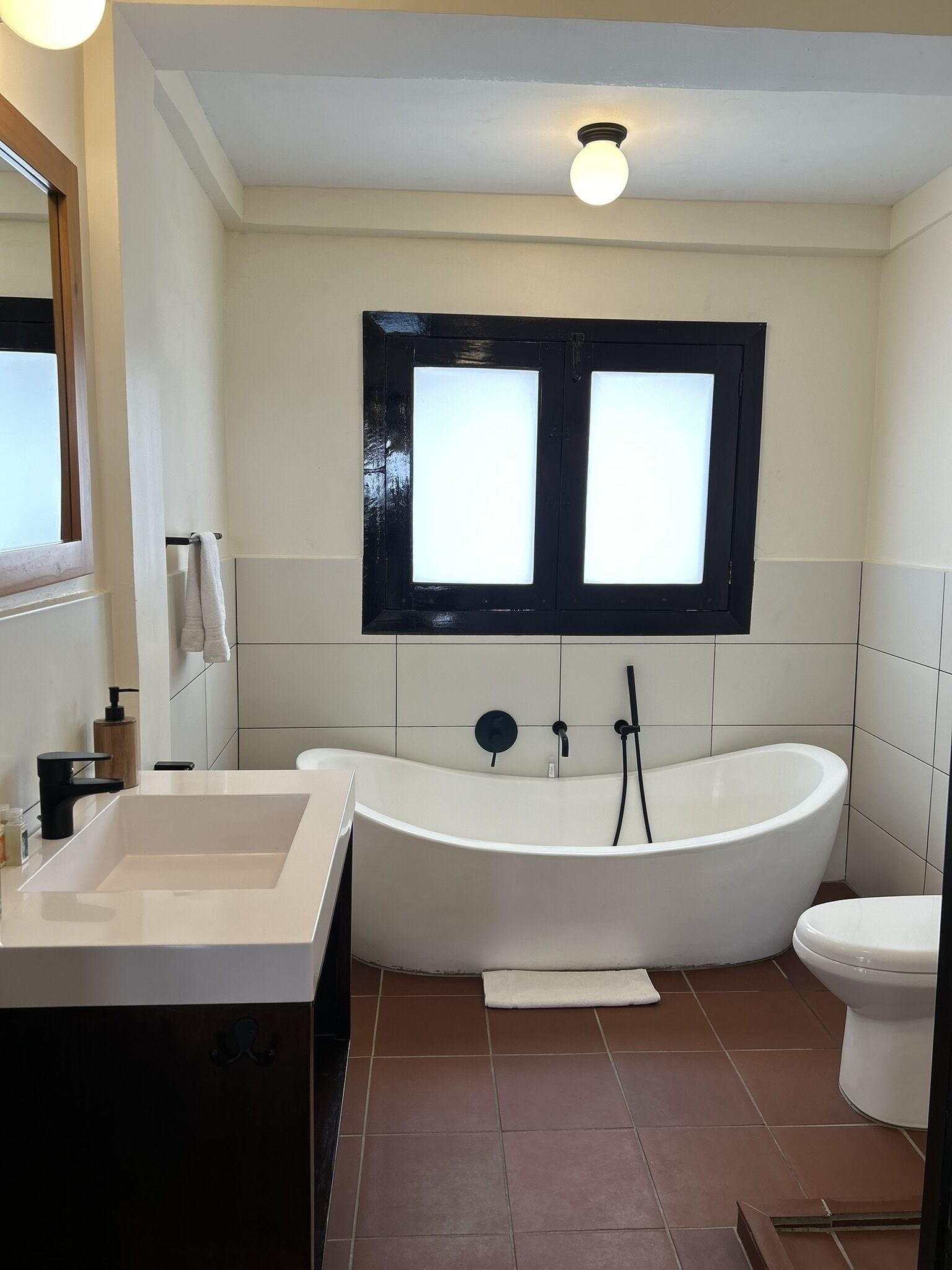 A modern bathroom with a freestanding bathtub, a toilet, and a sink.