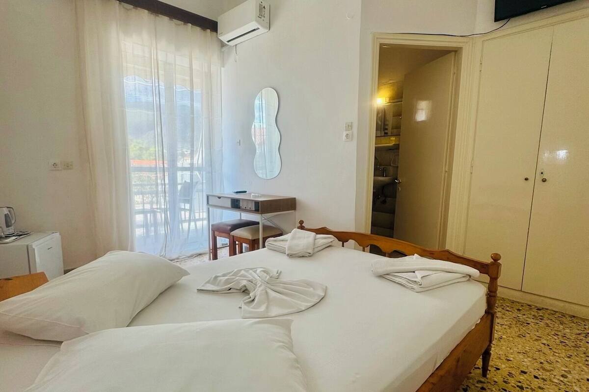 A hotel room with a bed, a desk, a chair, a wardrobe, and a television.