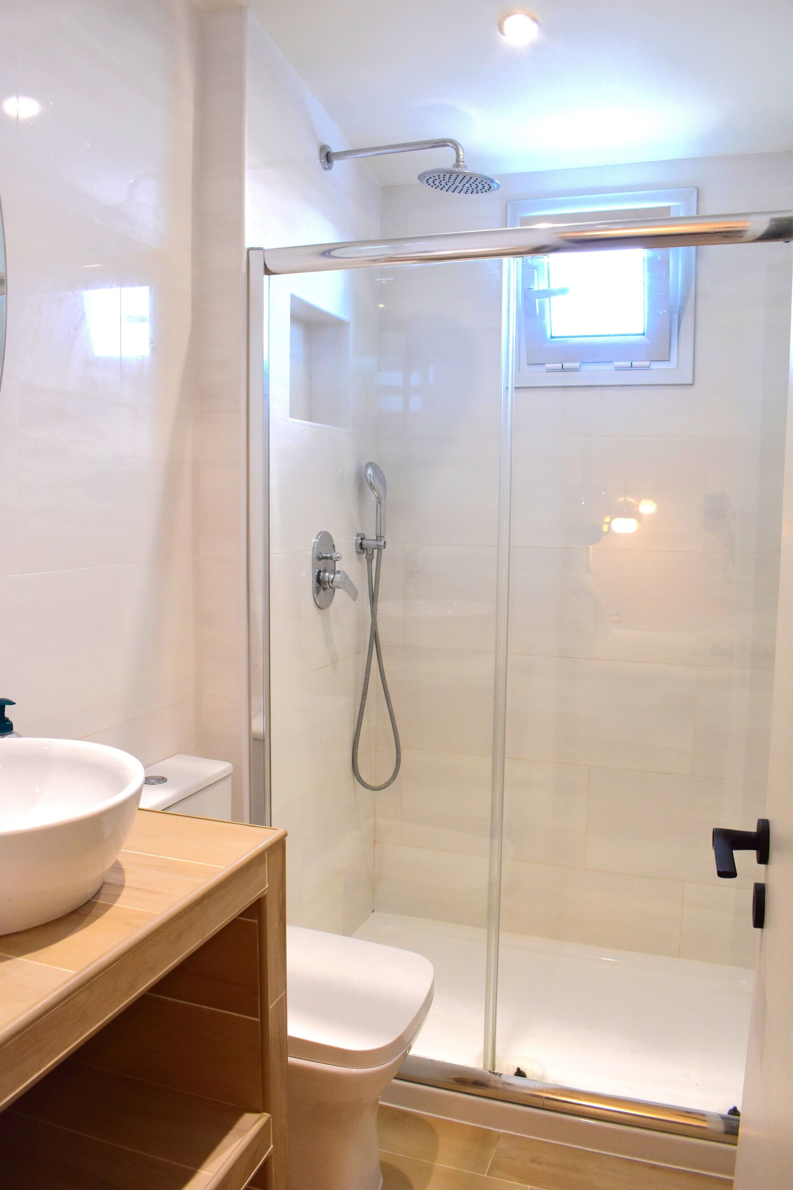 Une salle de bain moderne avec une douche à parois de verre, un lavabo blanc et des toilettes.
