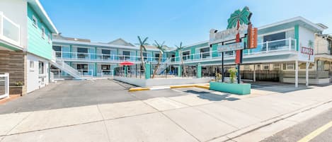 Un hôtel situé en bord de mer, doté d’une piscine, de palmiers et d’une enseigne indiquant le « Mango Bar ».