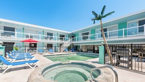 Un hotel con area piscina, inclusi lettini e vasca idromassaggio.