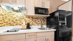 Una cucina moderna con un frigorifero nero, un forno a microonde e un forno da incasso.