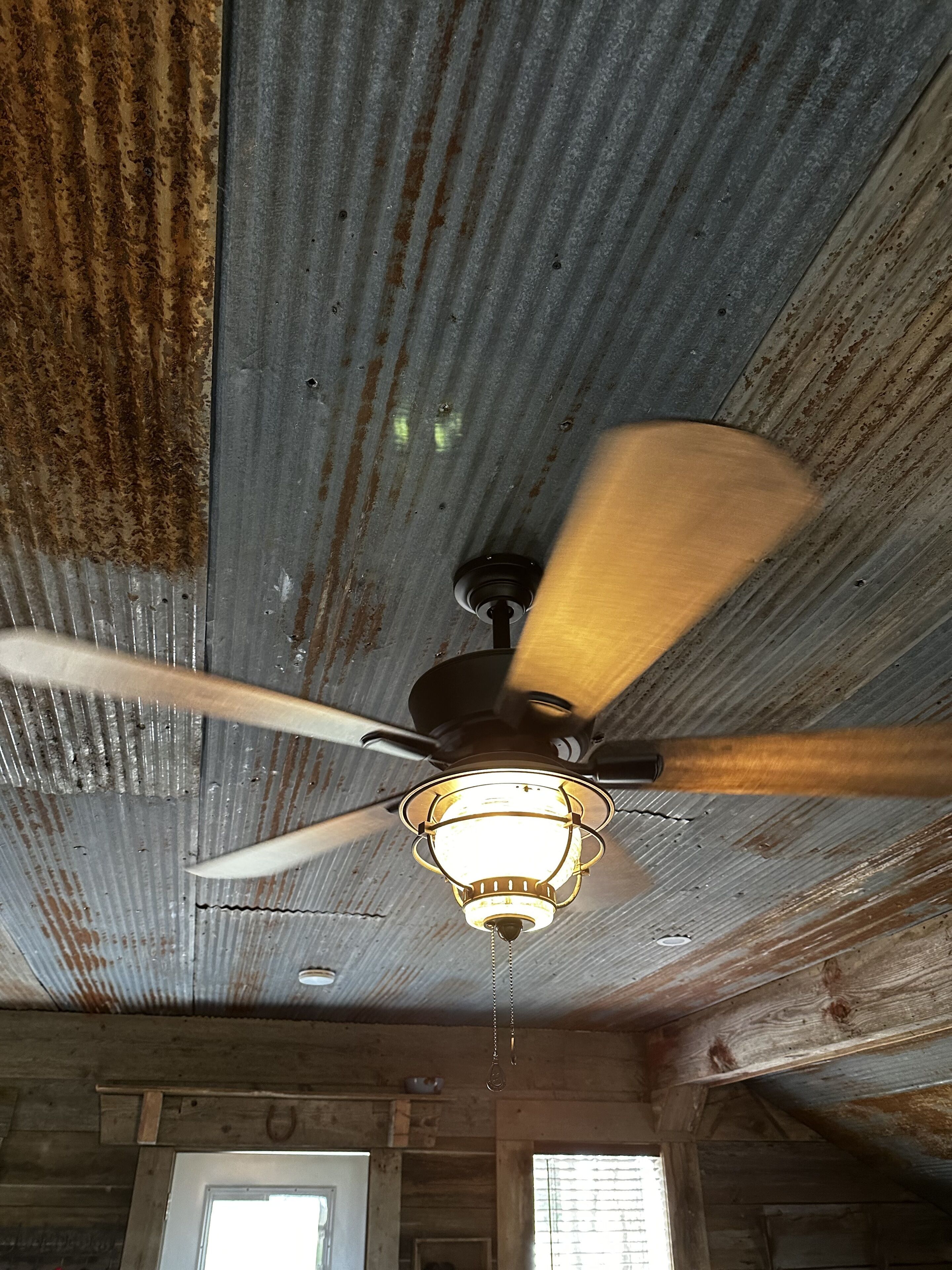There's a ceiling fan in the center of the room with multiple speeds.
