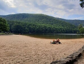 A sandy beach with a lake and forested hills in the background. - Cozy Country small two bedroom home. (Roseland)