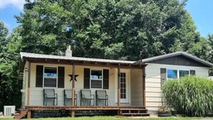 Une petite cabane à un seul étage, dotée d’une véranda et de plusieurs chaises.