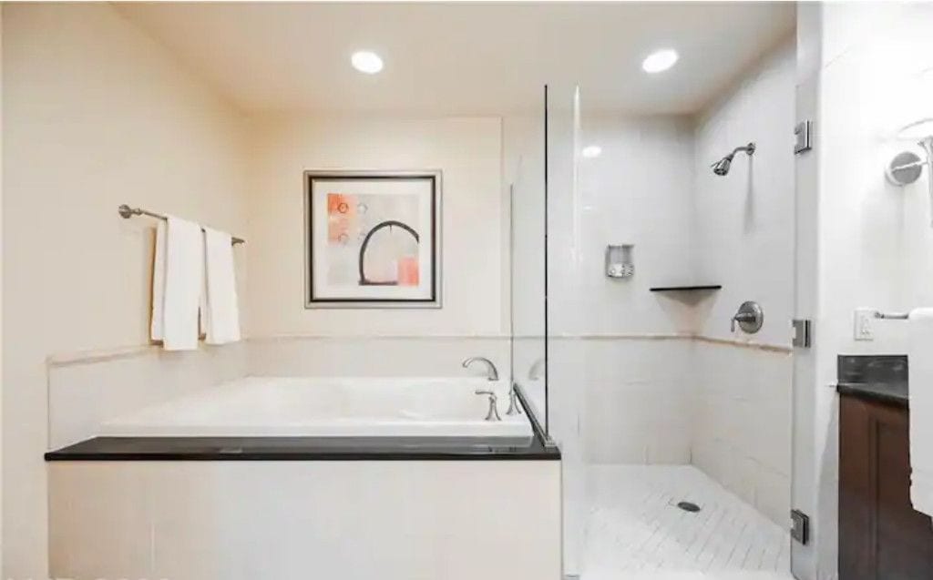 A modern bathroom with a large bathtub, a shower area, and a glass-enclosed shower stall.