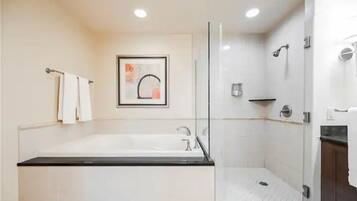 A modern bathroom with a large bathtub, a shower area, and a glass-enclosed shower stall.