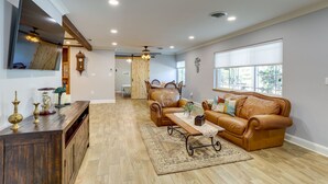 Un amplio salón con una mesa de centro de madera, sofás de cuero y un gran ventanal que proporciona luz natural.