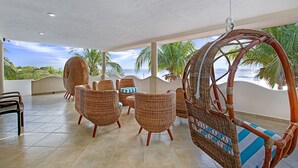 A covered outdoor seating area with wicker furniture and a view of the ocean. - Casa Kauil, an oceanfront villa in Celestun (Celestún)