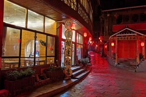 Un edificio tradicional con un vestíbulo de baldosas, un letrero con caracteres chinos y un sendero iluminado con luz roja.