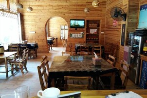 A wooden interior with tables and chairs, a television, and a refrigerator.