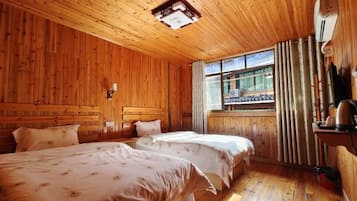 A wooden cabin room with two beds, a window with curtains, a lamp, and a wooden ceiling.