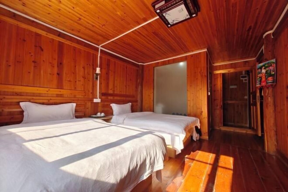 Een houten chalet met twee bedden, een houten plafond en een deur naar een andere kamer.