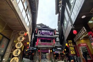 A narrow street with traditional architecture, including a building with a balcony and signage.