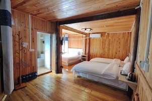 Una habitación con paneles de madera, dos camas, una mesita y una puerta que da a otra estancia.