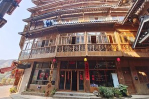 A traditional multi-story building with a wooden facade, balconies, and a storefront with signage. - Dongzhai Xiangfeng Inn (Sanjiang)